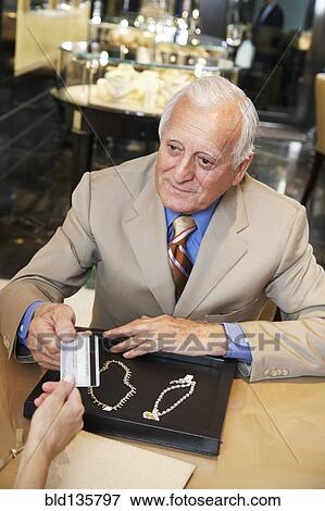 Stock Photo - Businessman purchasing jewelry with credit card. Fotosearch