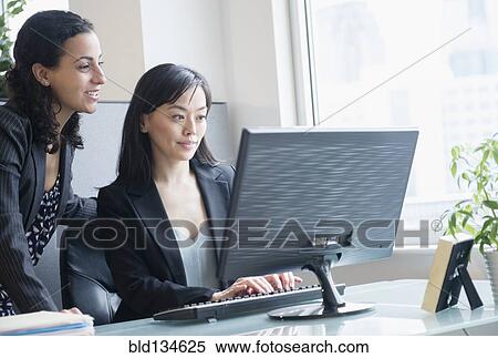 Stock Photography - Businesswomen working together in office. Fotosearch