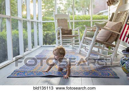Stock Image - Caucasian baby crawling on porch. Fotosearch
