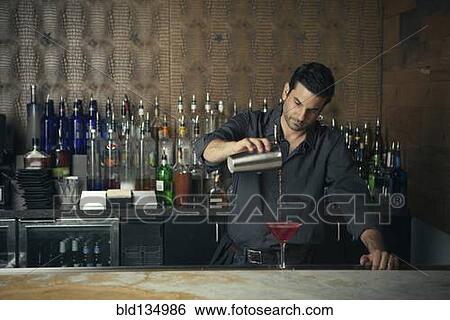 Stock Photograph - Caucasian bartender pouring drinks at bar. Fotosearch