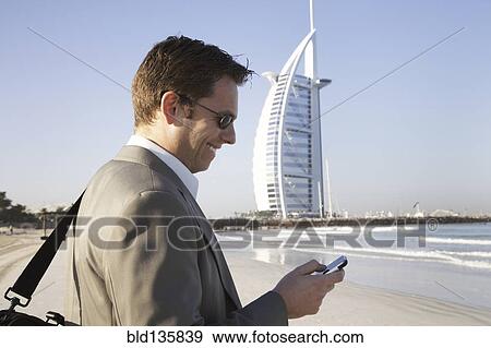 Caucasian businessman using cell phone on beach, Dubai, United Arab Emirates View Large Photo Image Stock Photo - Caucasian businessman using cell phone on beach, Dubai, United Arab Emirates. Fotosearch