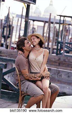 Caucasian couple sharing chair on city street View Large Photo Image Stock Image - Caucasian couple sharing chair on city street. Fotosearch