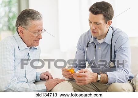 Stock Image - Caucasian doctor and patient discussing medication at home. Fotosearch