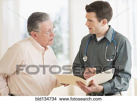 Picture - Caucasian doctor and patient talking in office. Fotosearch