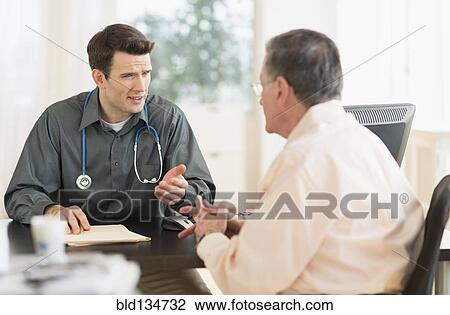 Stock Image - Caucasian doctor and patient talking in office. Fotosearch
