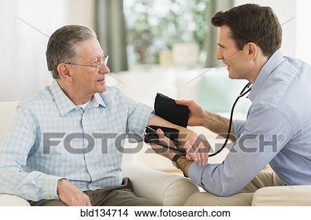 Caucasian doctor taking patient's blood pressure at home View Large Photo Image Picture - Caucasian doctor taking patient's blood pressure at home. Fotosearch