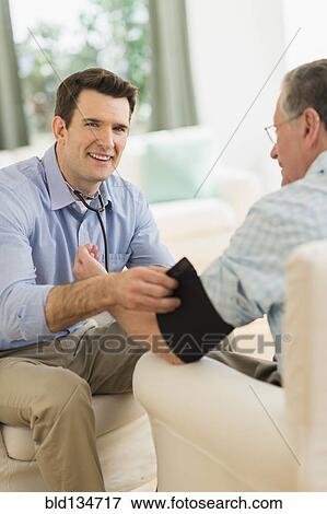 Caucasian doctor taking patient's blood pressure at home View Large Photo Image Stock Photo - Caucasian doctor taking patient's blood pressure at home. Fotosearch