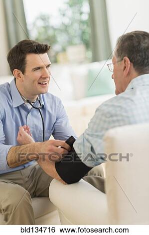 Caucasian doctor taking patient's blood pressure at home View Large Photo Image Stock Photograph - Caucasian doctor taking patient's blood pressure at home. Fotosearch