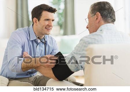 Stock Photography - Caucasian doctor taking patient's blood pressure at home. Fotosearch
