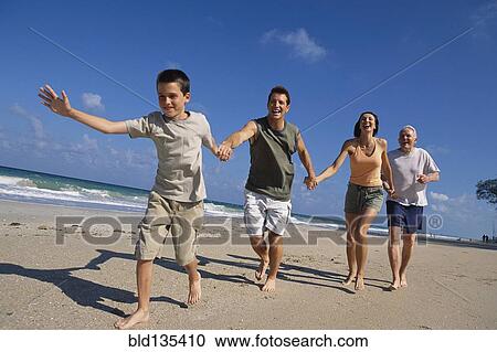 Stock Image - Caucasian family holding hands on beach. Fotosearch