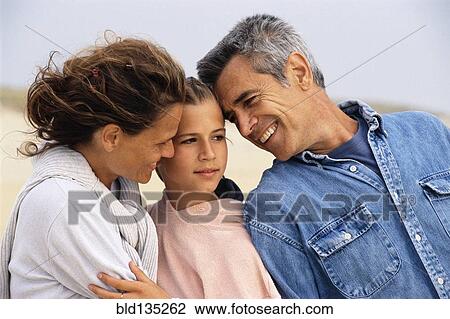 Stock Image - Caucasian family hugging on beach. Fotosearch