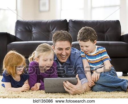 Caucasian father and children using tablet computer in living room View Large Photo Image Stock Photograph - Caucasian father and children using tablet computer in living room. Fotosearch
