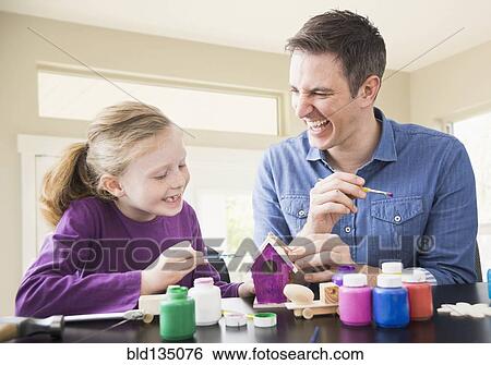 Stock Photograph - Caucasian father and daughter painting together. Fotosearch