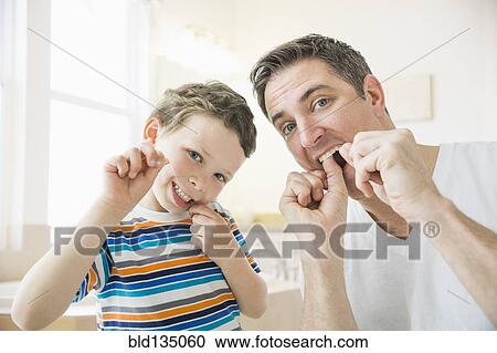 Stock Image - Caucasian father and son flossing their teeth. Fotosearch