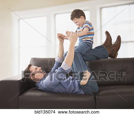 Caucasian father and son playing on sofa View Large Photo Image Picture - Caucasian father and son playing on sofa. Fotosearch