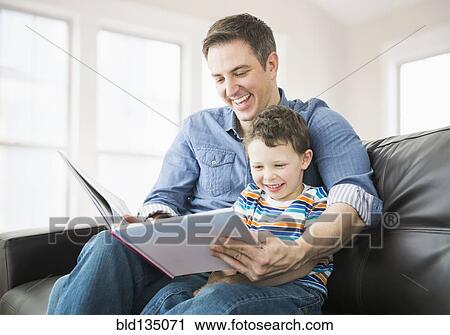 Caucasian father and son reading on sofa View Large Photo Image Stock Image - Caucasian father and son reading on sofa. Fotosearch