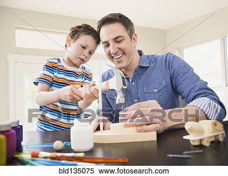 Stock Photography - Caucasian father teaching son wood crafts. Fotosearch