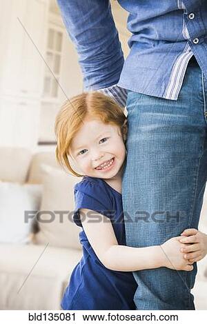 Stock Image - Caucasian girl clutching father's leg. Fotosearch