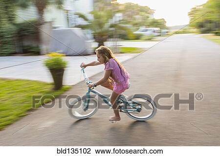 Stock Image - Caucasian girl riding bicycle on street. Fotosearch