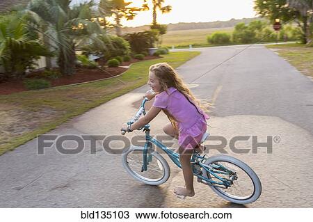 Stock Image - Caucasian girl riding bicycle on street. Fotosearch