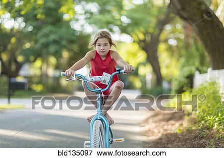 Stock Photo - Caucasian girl riding bicycle on street. Fotosearch
