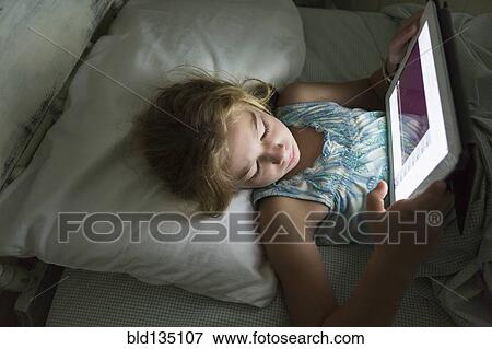 Caucasian girl using tablet computer in bed View Large Photo Image Stock Photo - Caucasian girl using tablet computer in bed. Fotosearch