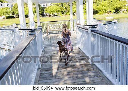 Picture - Caucasian girl walking with dog in gazebo. Fotosearch