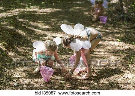 Stock Photo - Caucasian girls playing dress up in forest. Fotosearch