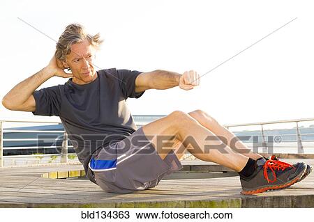 Stock Image - Caucasian man exercising in waterfront park. Fotosearch