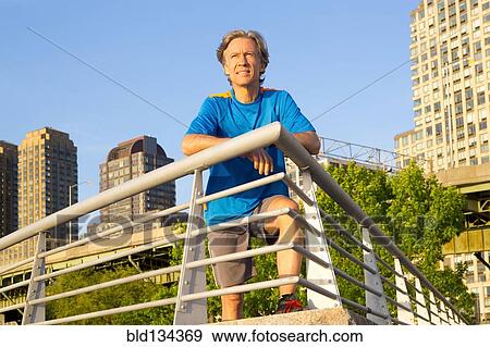 Stock Photo - Caucasian man leaning on railing in urban park. Fotosearch