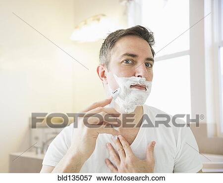Stock Photo - Caucasian man shaving in bathroom. Fotosearch