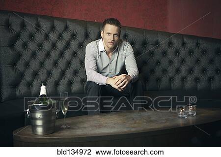 Stock Image - Caucasian man sitting in nightclub. Fotosearch