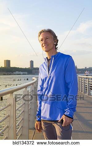 Stock Image - Caucasian man standing at urban waterfront. Fotosearch