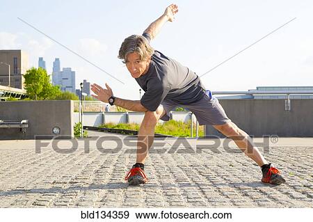 Caucasian man stretching in urban park View Large Photo Image Stock Photo - Caucasian man stretching in urban park. Fotosearch