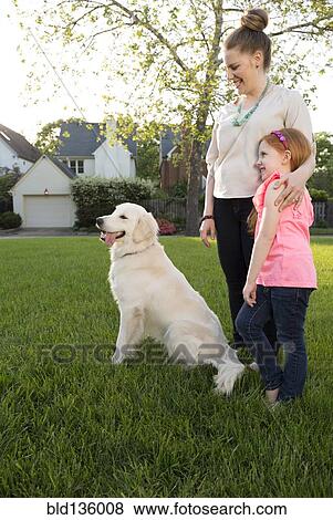Stock Photo - Caucasian mother and daughter with dog in park. Fotosearch