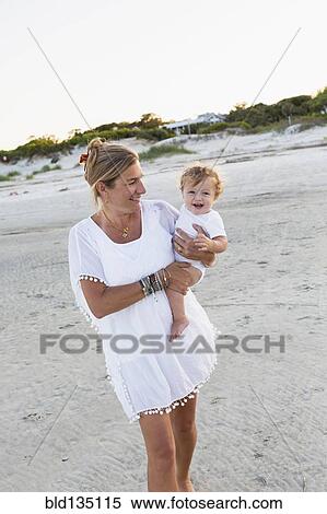 Caucasian mother carrying baby on beach View Large Photo Image Stock Photography - Caucasian mother carrying baby on beach. Fotosearch