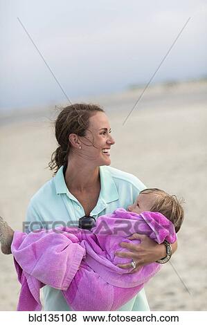 Caucasian mother carrying daughter on beach View Large Photo Image Stock Photo - Caucasian mother carrying daughter on beach. Fotosearch