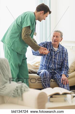 Caucasian nurse helping patient out of bed in home View Large Photo Image Picture - Caucasian nurse helping patient out of bed in home. Fotosearch