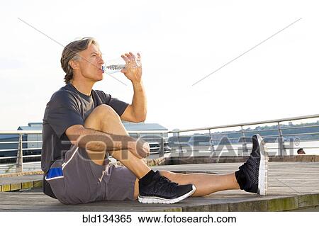Caucasian runner drinking water in waterfront park View Large Photo Image Stock Photography - Caucasian runner drinking water in waterfront park. Fotosearch