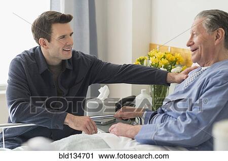 Stock Image - Caucasian son visiting father in hospital. Fotosearch