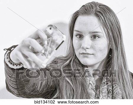 Stock Image - Caucasian teenage girl taking picture with cell phone. Fotosearch