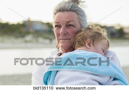 Caucasian woman carrying grandson on beach View Large Photo Image Stock Image - Caucasian woman carrying grandson on beach. Fotosearch