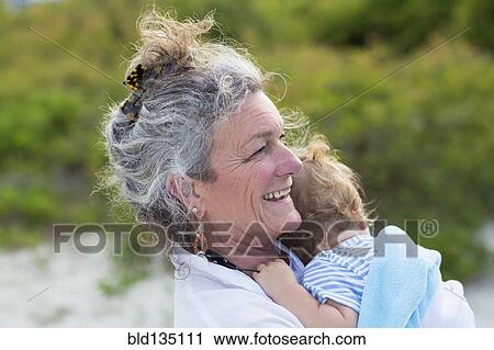 Caucasian woman carrying grandson on beach View Large Photo Image Stock Image - Caucasian woman carrying grandson on beach. Fotosearch
