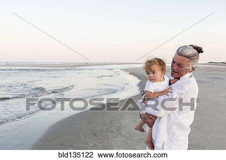 Caucasian woman carrying grandson on beach View Large Photo Image Stock Image - Caucasian woman carrying grandson on beach. Fotosearch