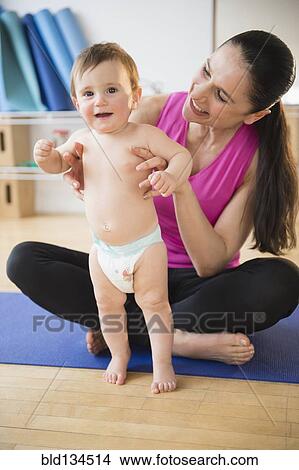 Caucasian woman holding baby on yoga mat View Large Photo Image Picture - Caucasian woman holding baby on yoga mat. Fotosearch
