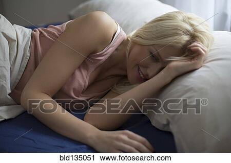 Stock Image - Caucasian woman laying in bed. Fotosearch
