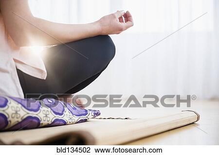 Stock Image - Caucasian woman meditating on yoga mat. Fotosearch