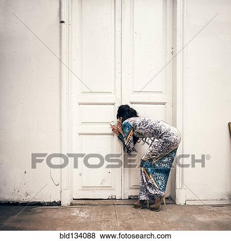 Caucasian woman peering through keyhole View Large Photo Image Stock Photo - Caucasian woman peering through keyhole. Fotosearch