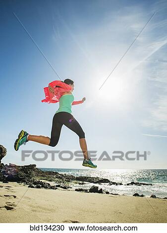 Stock Image - Caucasian woman running on beach. Fotosearch