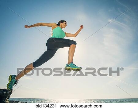 Stock Image - Caucasian woman running on beach. Fotosearch